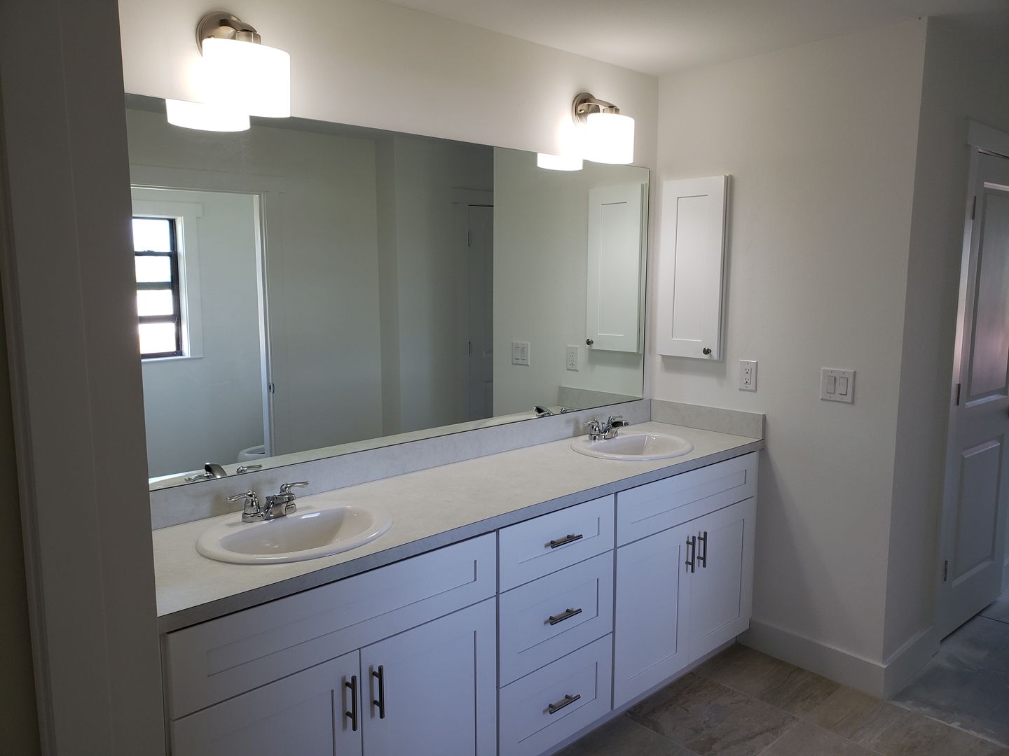 A bathroom with two sinks and a large mirror built by Blue Heron Construction Cape Coral