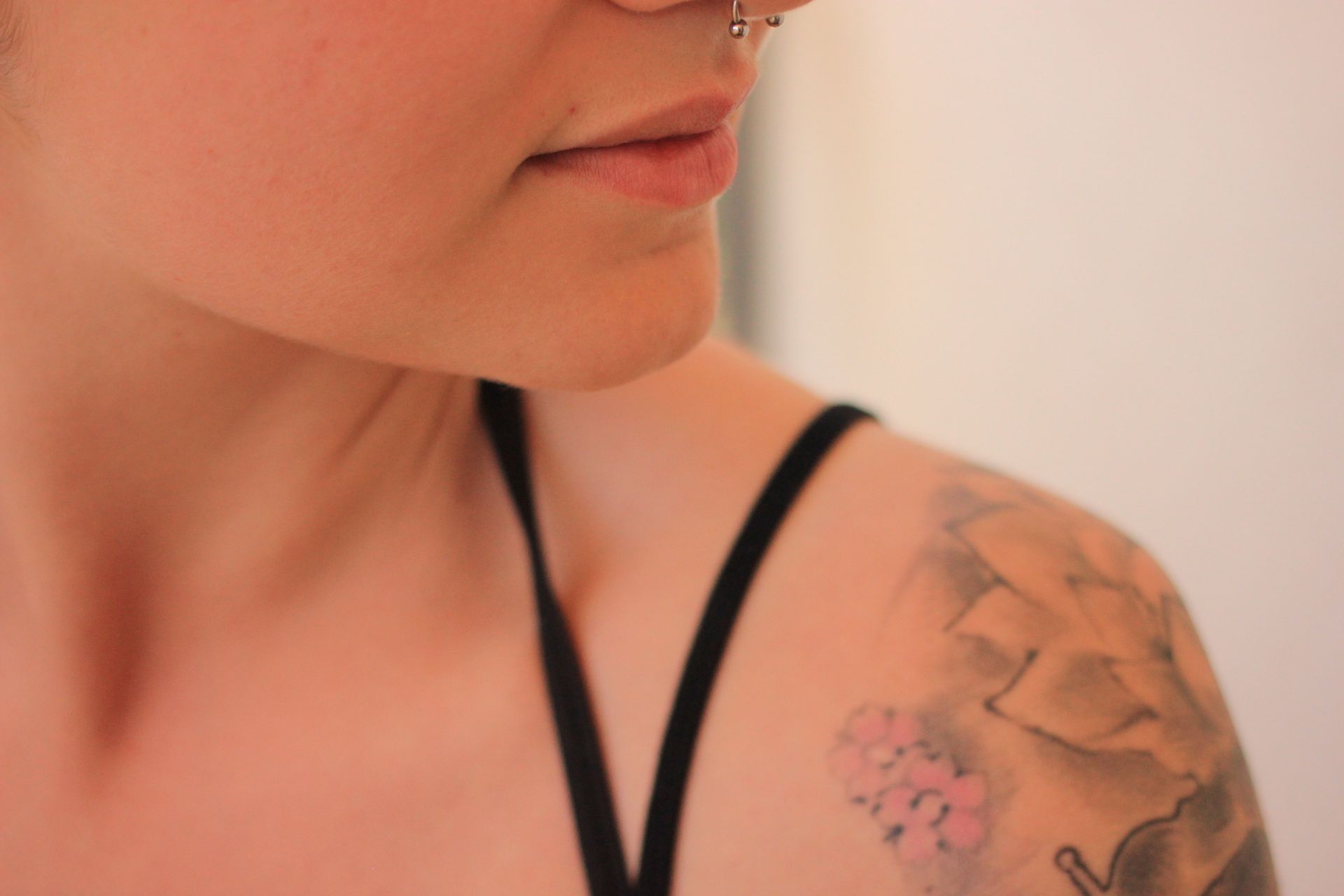 Person with nose ring and shoulder tattoo, wearing a black top.
