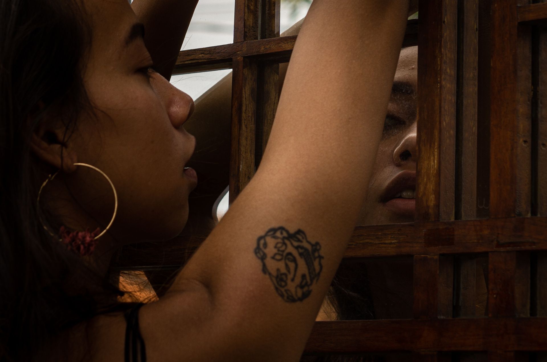 A woman with a tattoo on her arm is looking at her reflection in a mirror.
