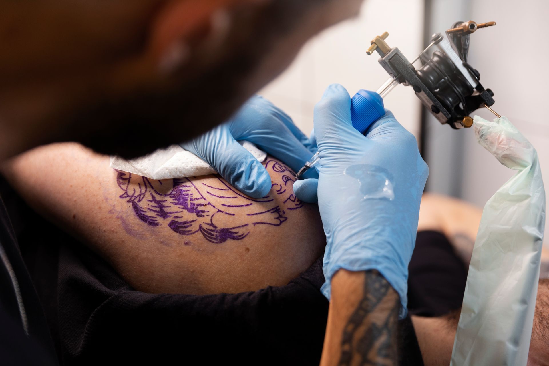 A man is getting a tattoo on a woman 's arm.