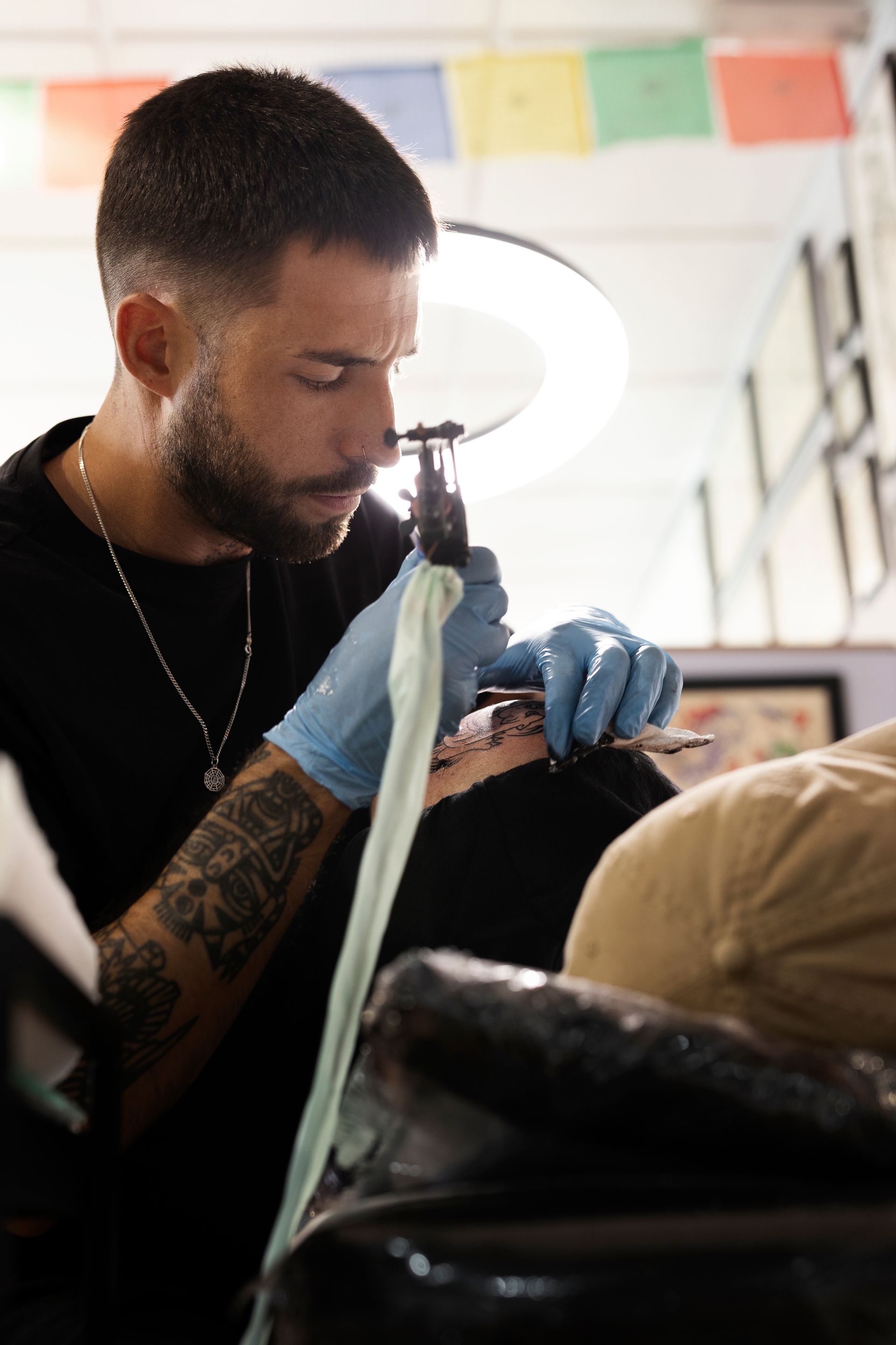 A man is getting a tattoo on another man 's face.