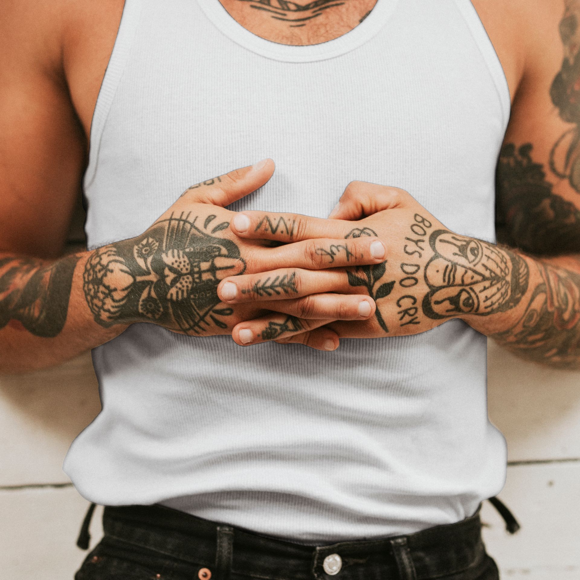 A man in a tank top has a tattoo on his hand that says boys do cry