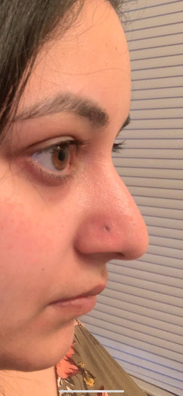 A close up of a woman 's face with a nose piercing.