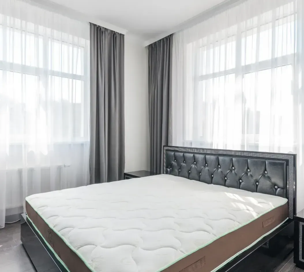 There is a bed with a mattress in the middle of the room.