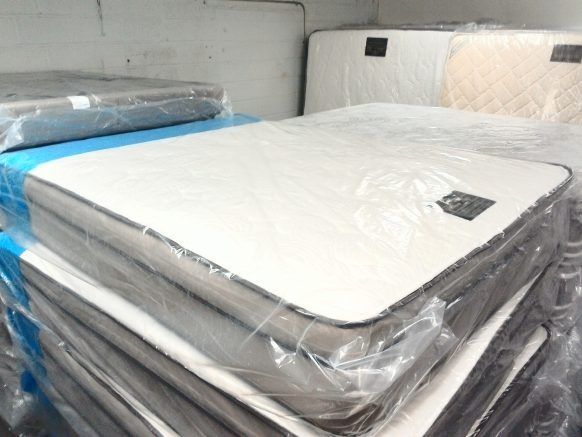 A stack of white mattresses wrapped in plastic