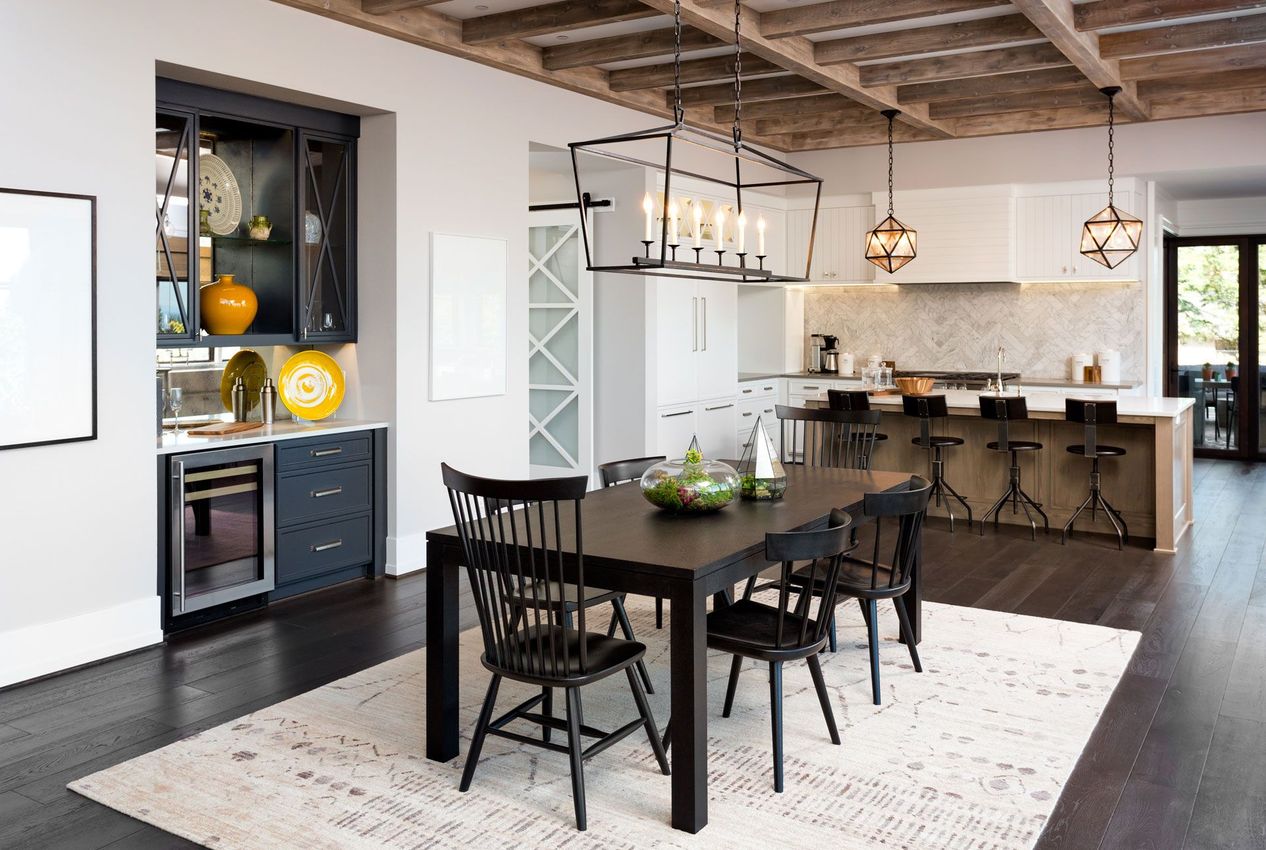 a dining room with a table and chairs and a kitchen in the background .