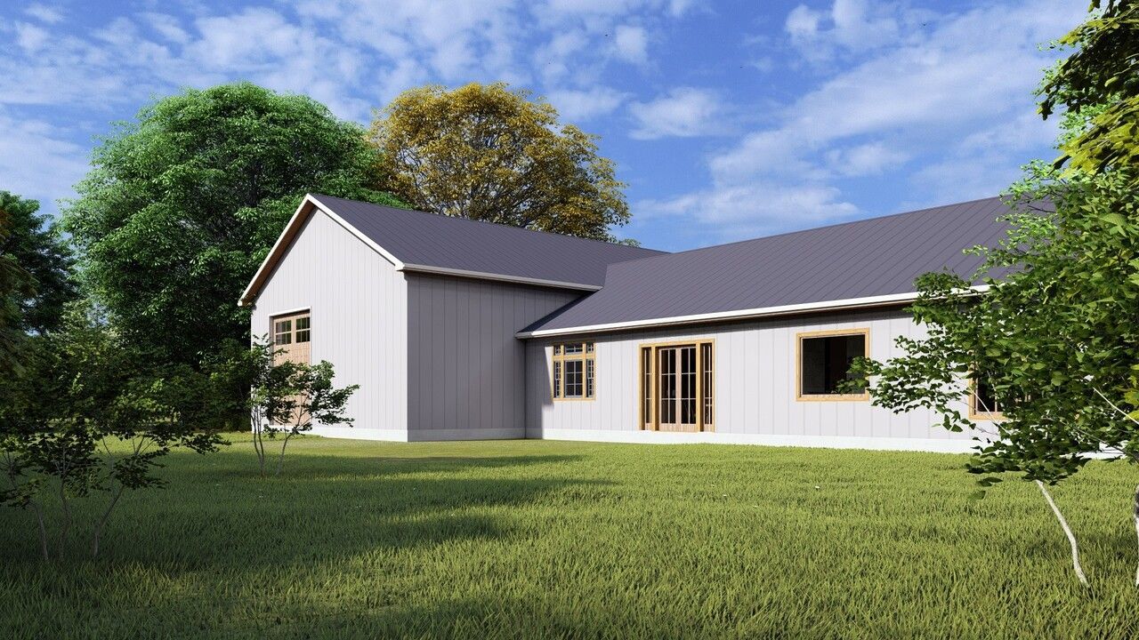 A white house with a gray roof is sitting in the middle of a lush green field.