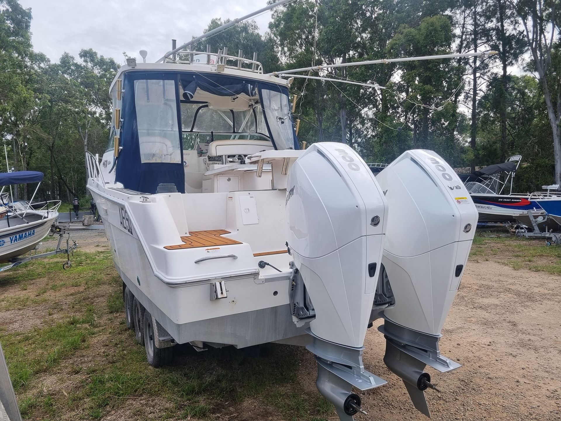 A row of outboard motors are lined up on the shore of a lake.