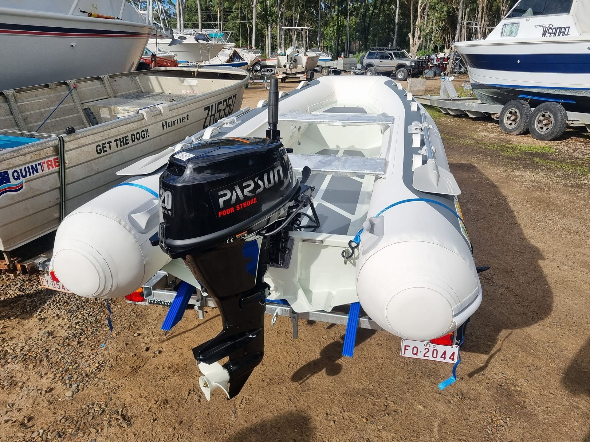 The engine of a boat is sitting in front of a thatched hut.