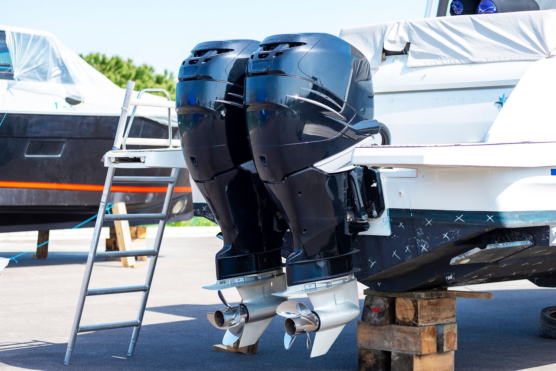 A boat with two outboard engines is sitting on a wooden block.