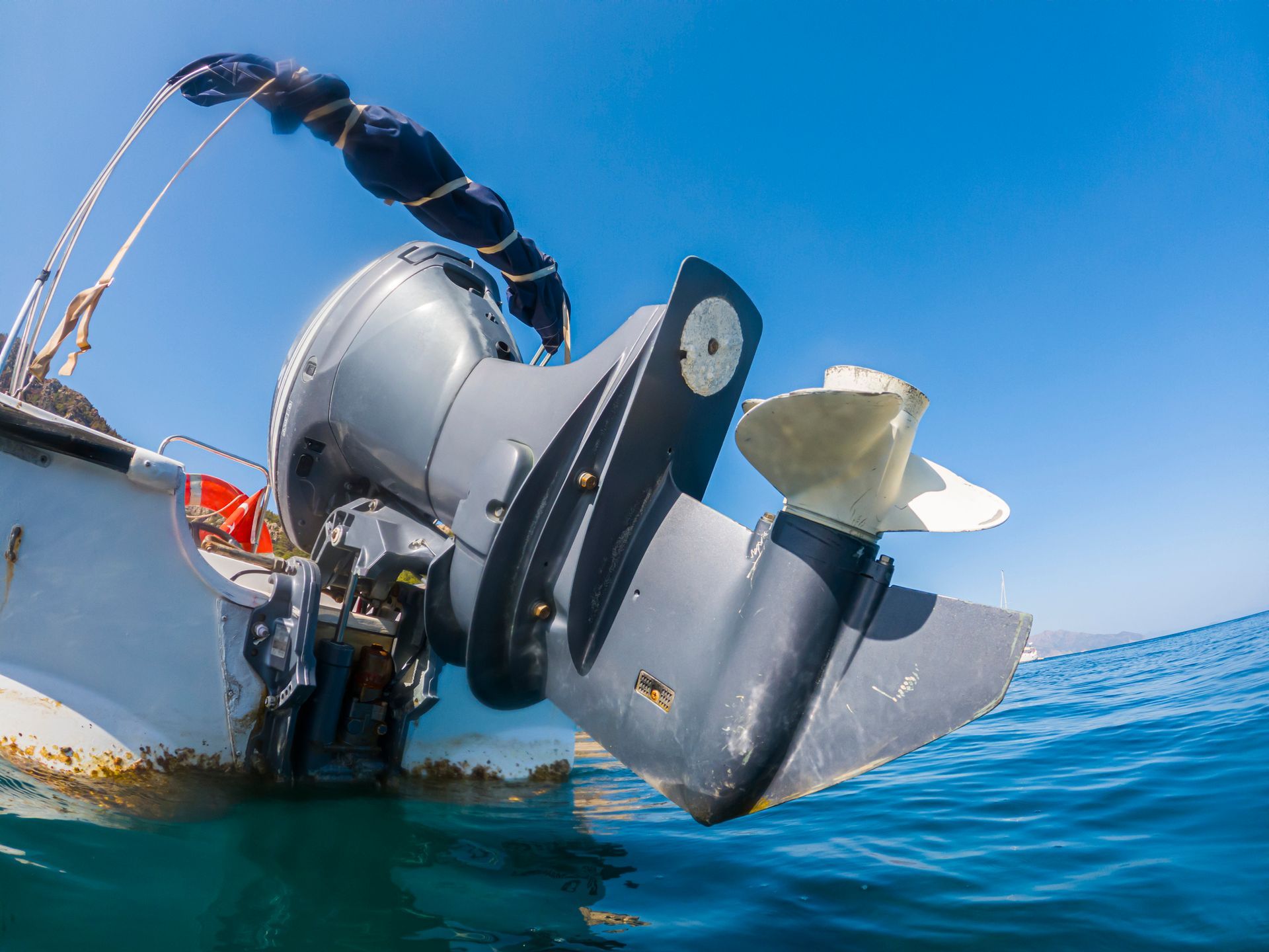 A boat with an outboard motor is floating on top of a body of water.