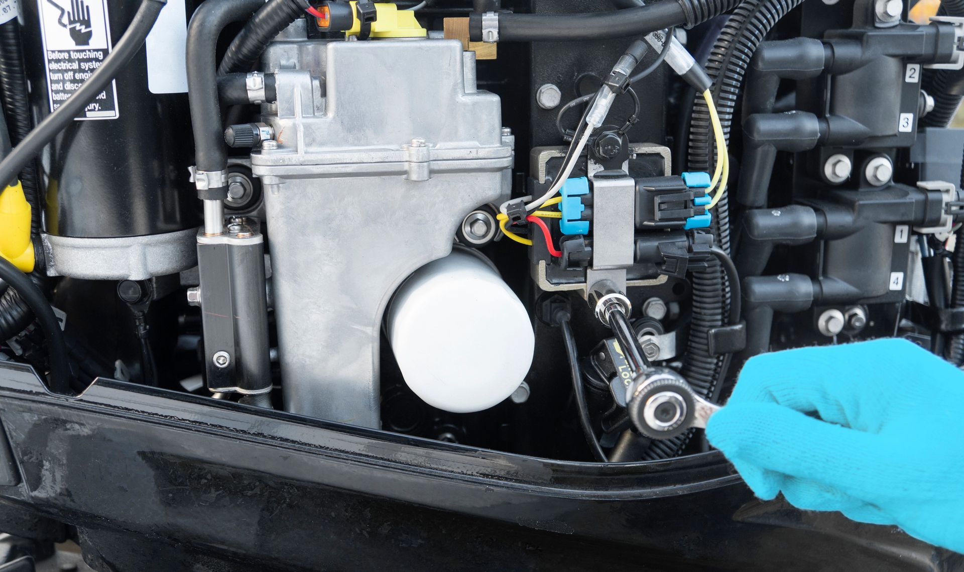 A person wearing blue gloves is working on a boat engine.