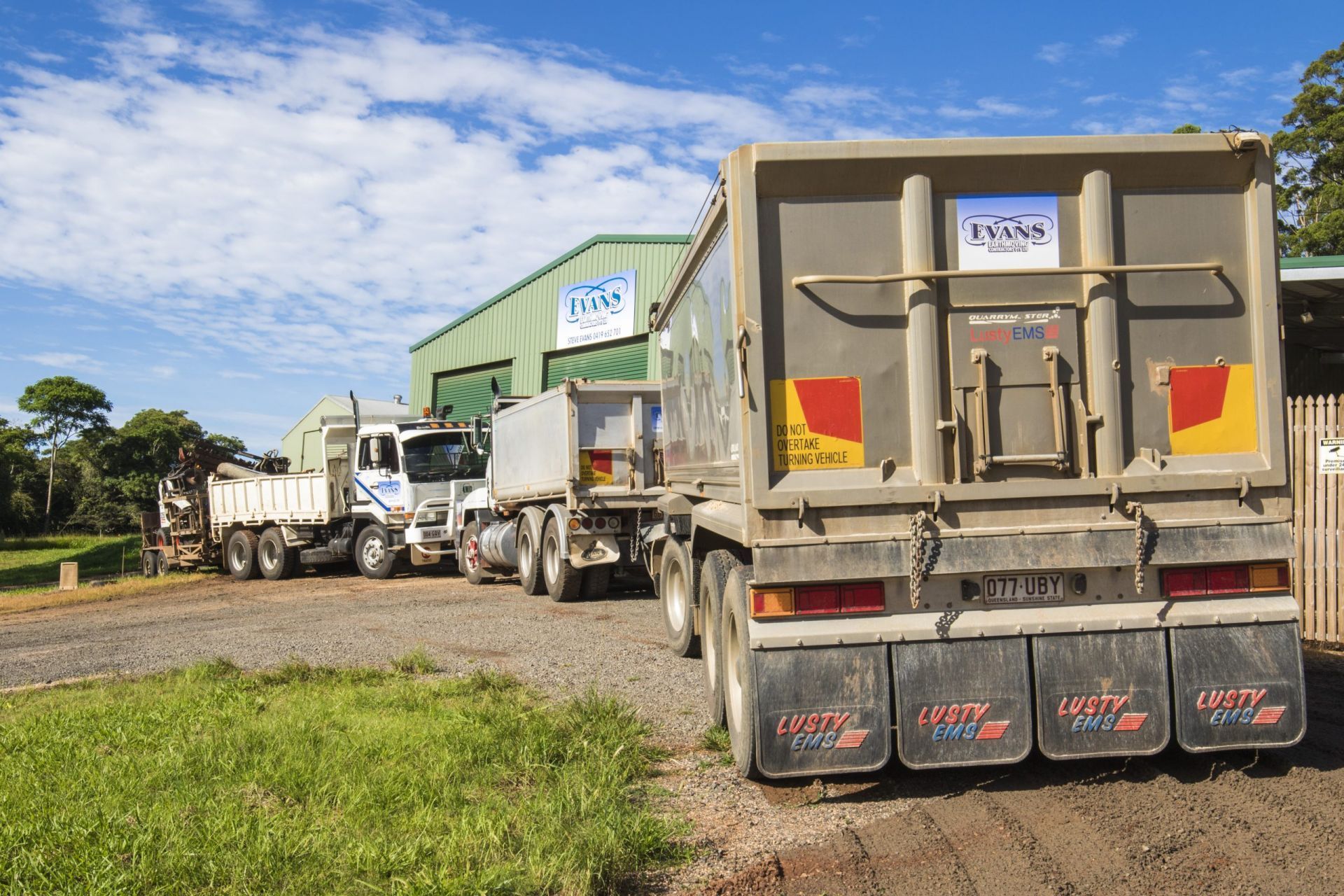 Trucks Lined up Outside a Building — Evans Earthmoving Contractors In Malanda, QLD