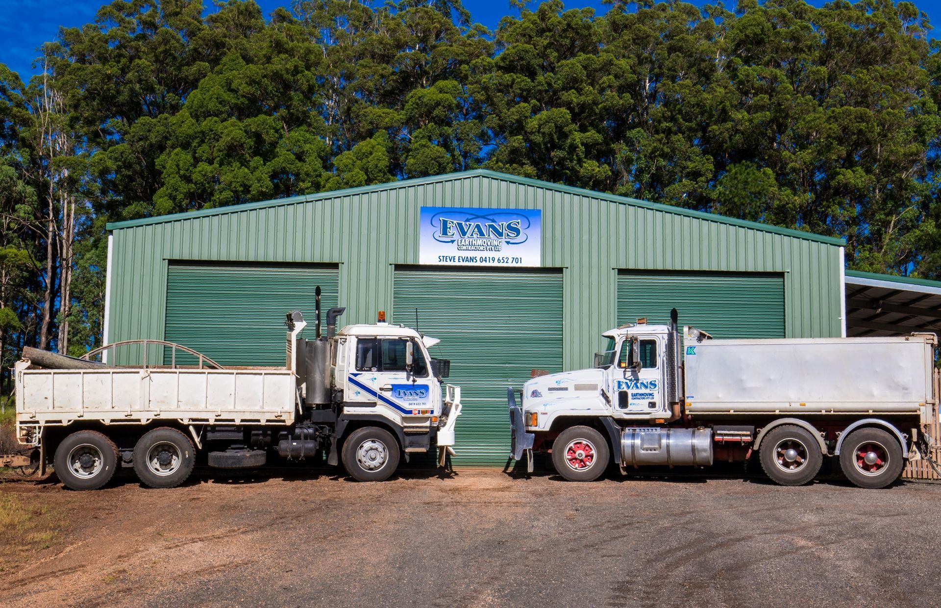 Two Work Trucks Parked in Front of A Green Shed — Evans Earthmoving Contractors In Malanda, QLD