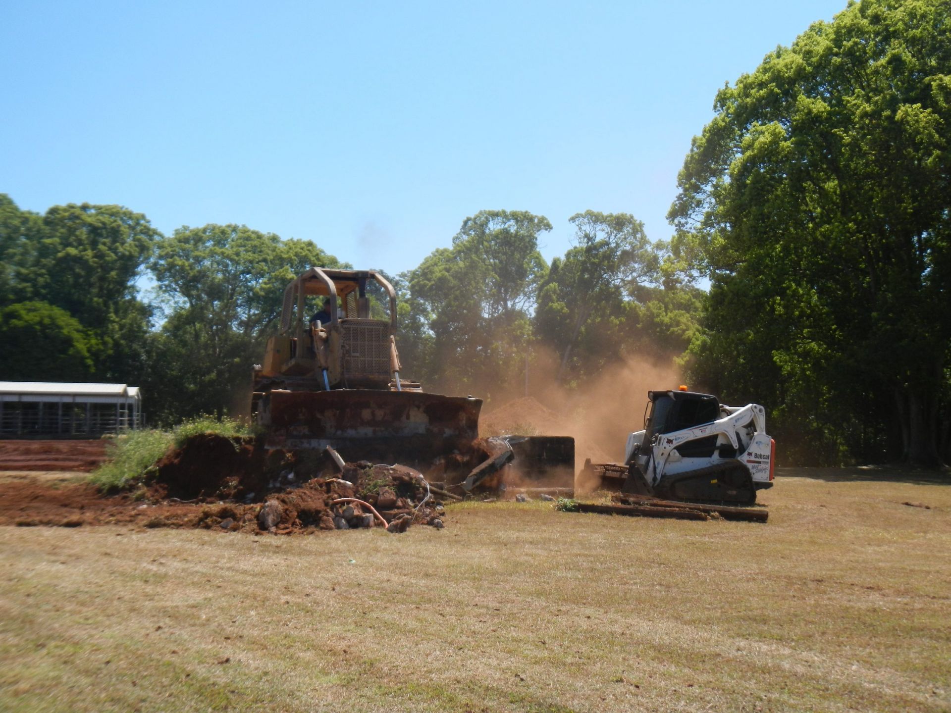 A Skid Steer and Demolition Equipment Tear Down a Structure Outdoors — Evans Earthmoving Contractors In Malanda, QLD 