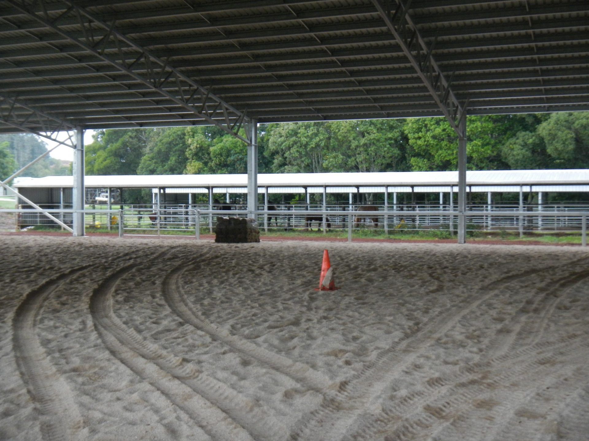 Equestrian Arena with Dirt Surface and Tire Tracks Under a Covered Structure with Trees in The Background — Evans Earthmoving Contractors In Malanda, QLD