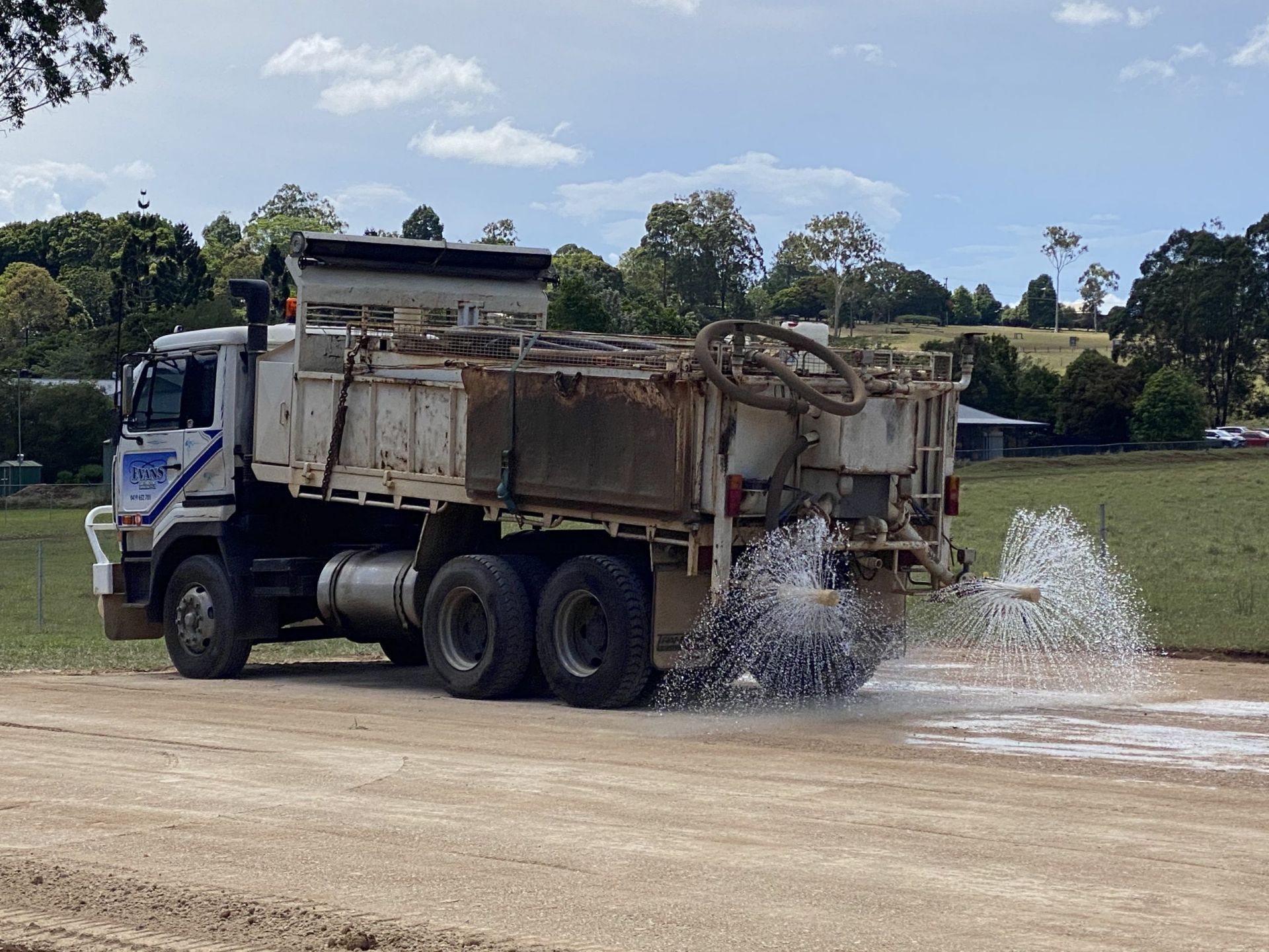 Dump Truck Emptying Water Beside a Lake on a Dirt Road — Evans Earthmoving Contractors In Mareeba, QLD