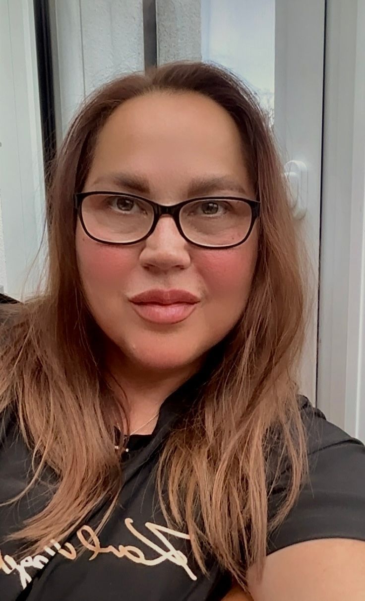 Eine Frau trägt ein weißes Hemd und eine Halskette mit einem Kreuz.