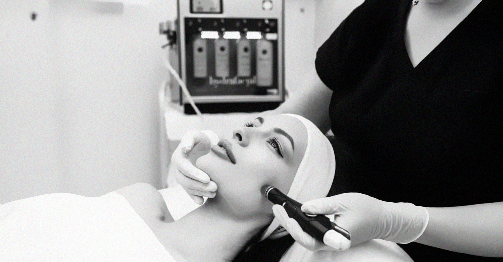 Ein Schwarzweißfoto des Gesichts einer Frau neben einer Flasche Microneedling-Stift.