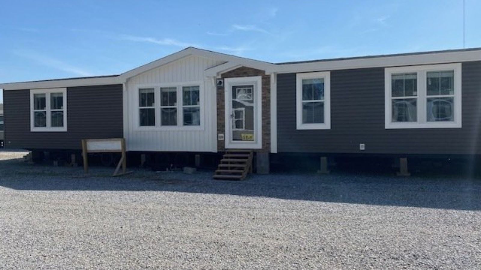 Exterior view of a large double wide manufactured home with steps leading to the front door