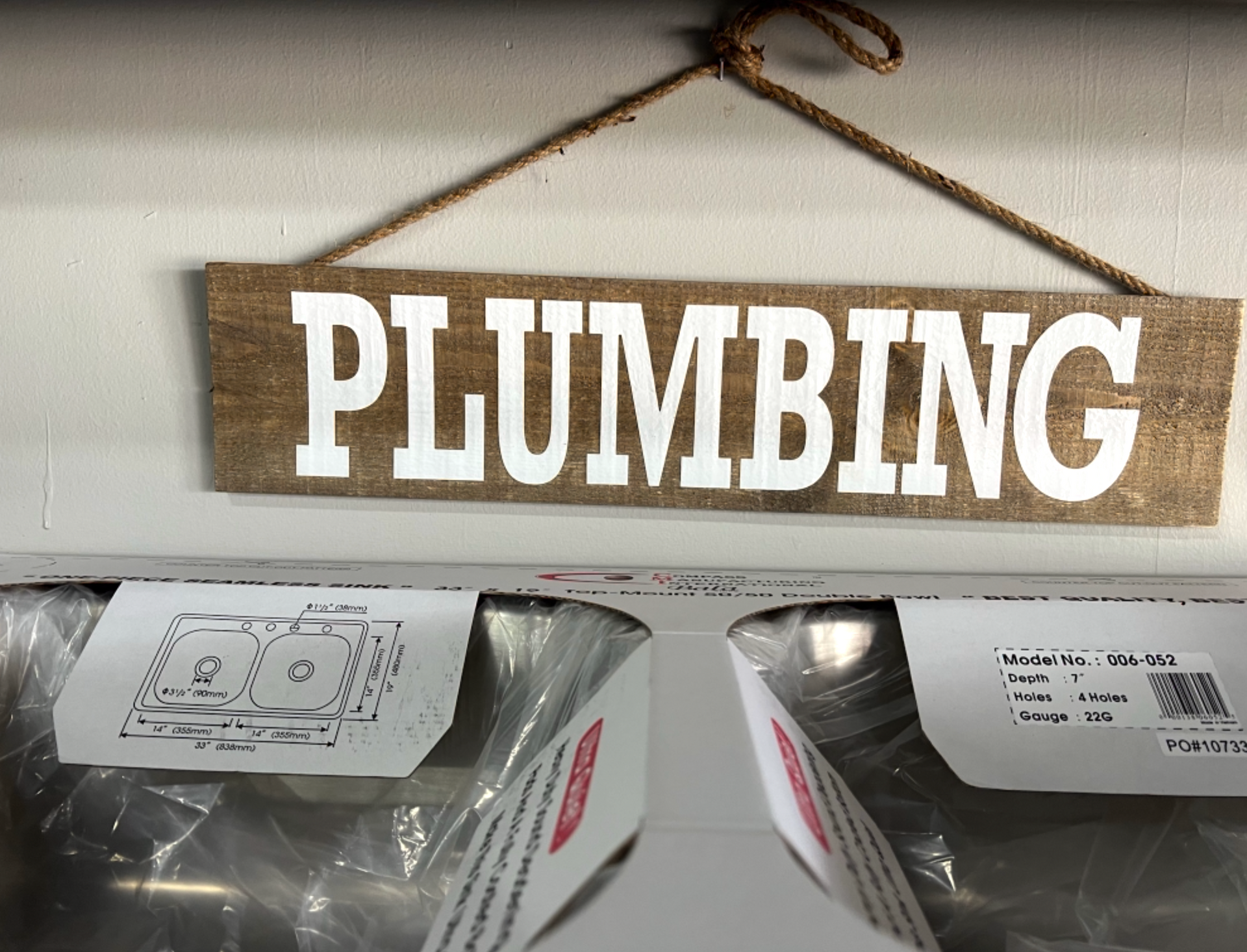 A sign that says plumbing hangs above a sink