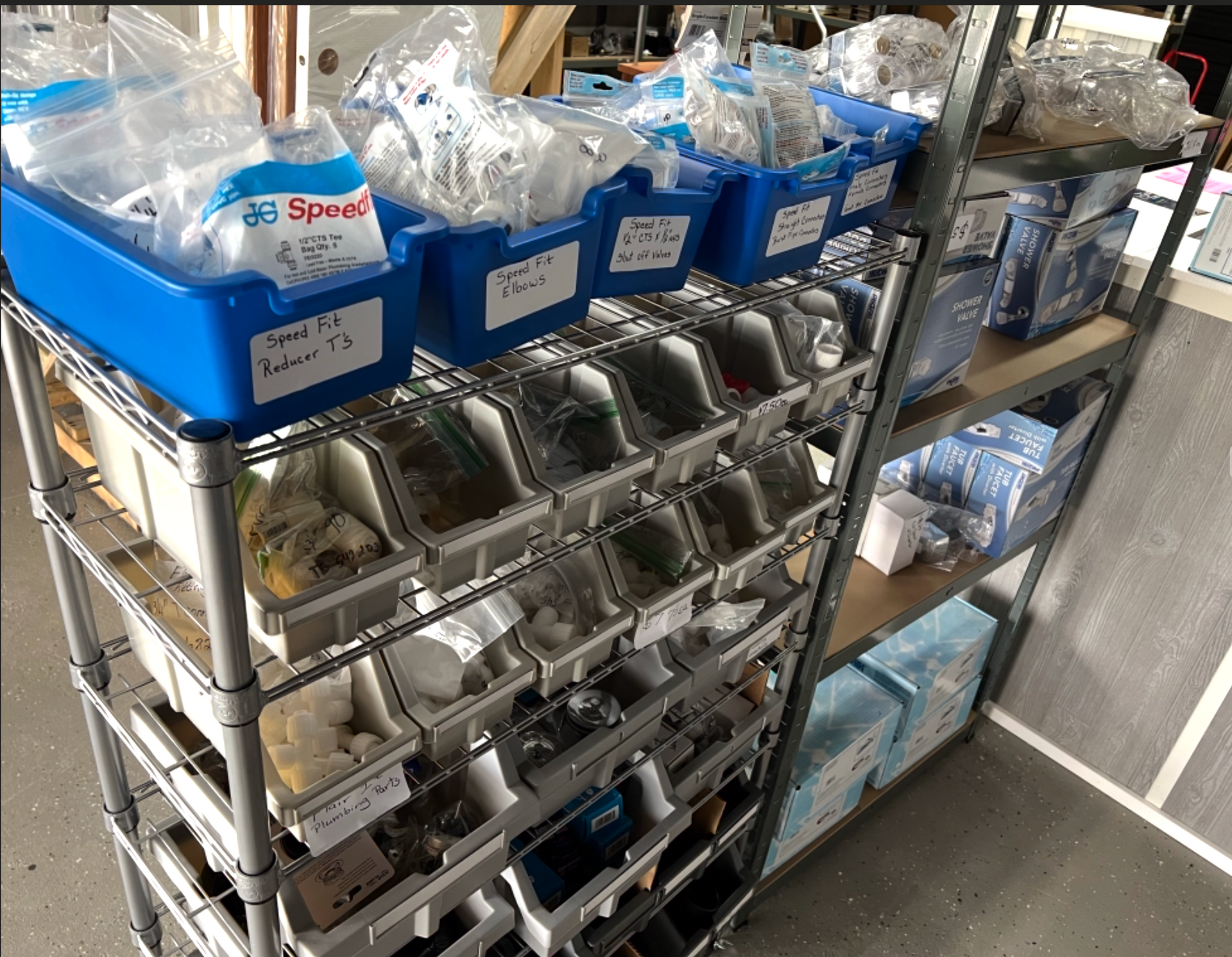 A shelf filled with lots of blue bins filled with various items.