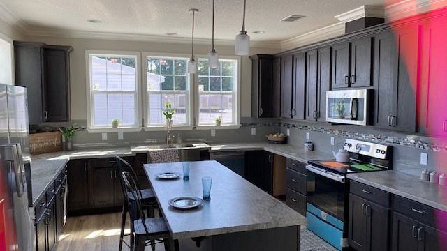 a manufactured home kitchen with black cabinets , stainless steel appliances , a large island , and a stove .