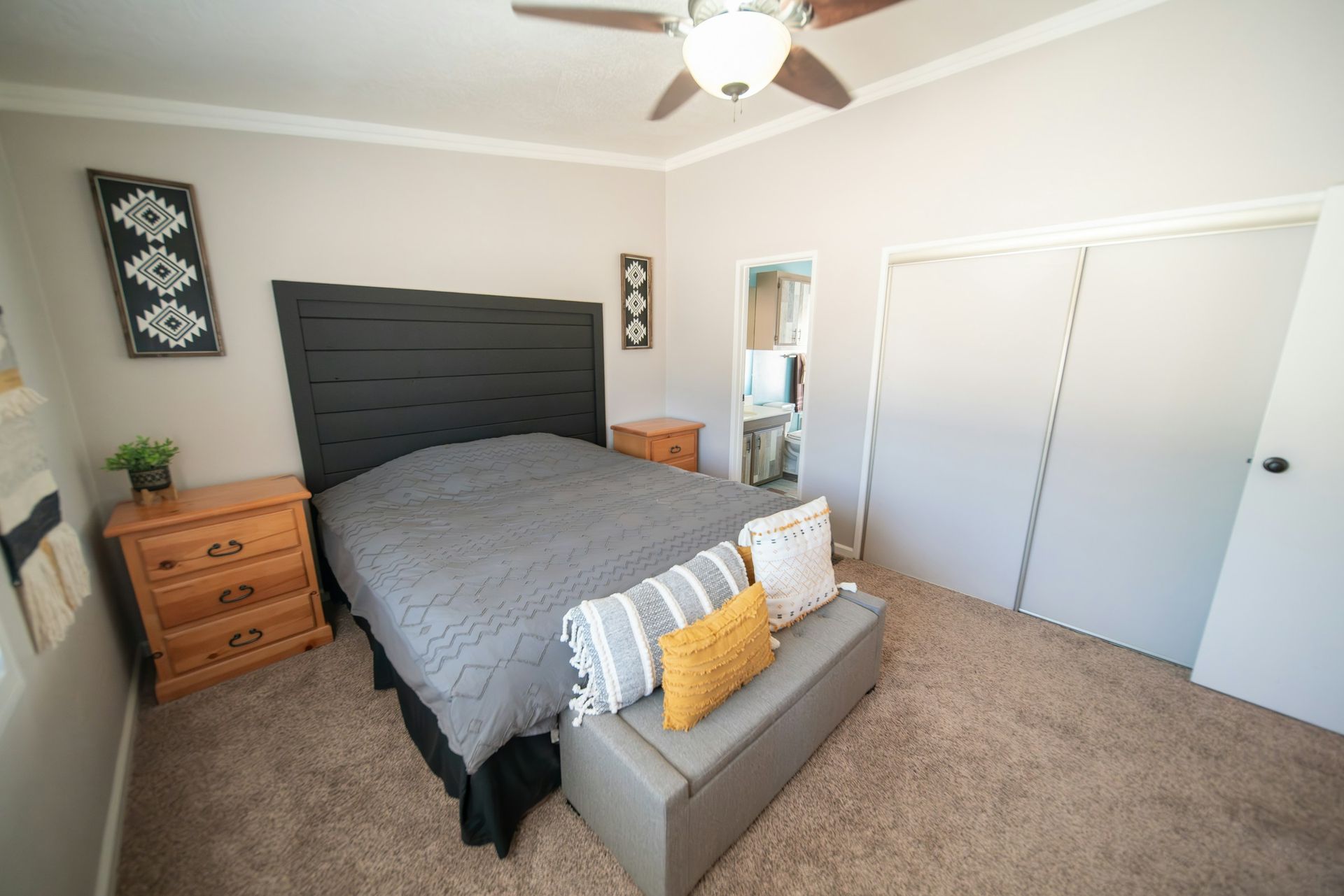 A bedroom with a bed , dresser , nightstand and ceiling fan.