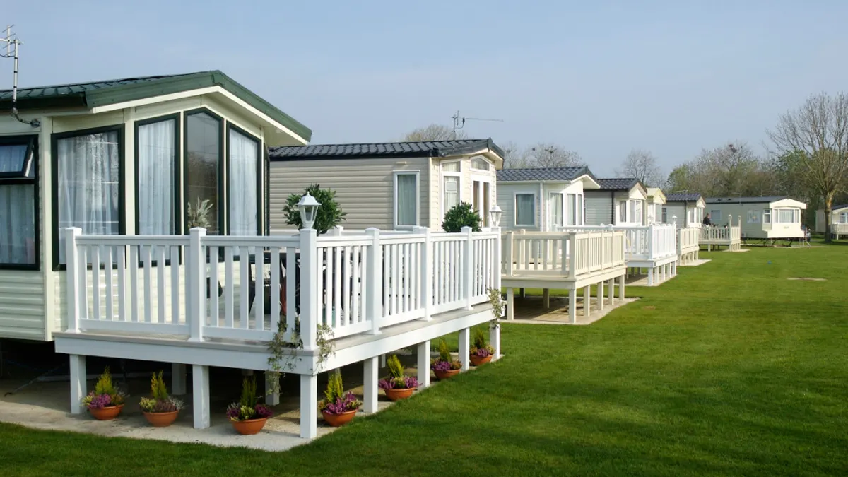 “Row of modern manufactured homes with white porch railings and landscaped lawns in a mobile home co