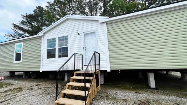 Single-wide manufactured home with light green siding and a small entry staircase.