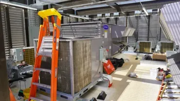 Industrial workshop with a large metal crate, orange ladder, and tools on the floor