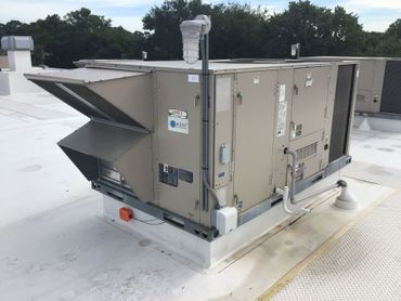 Large rooftop HVAC unit with metal vents and ductwork on a white roof.