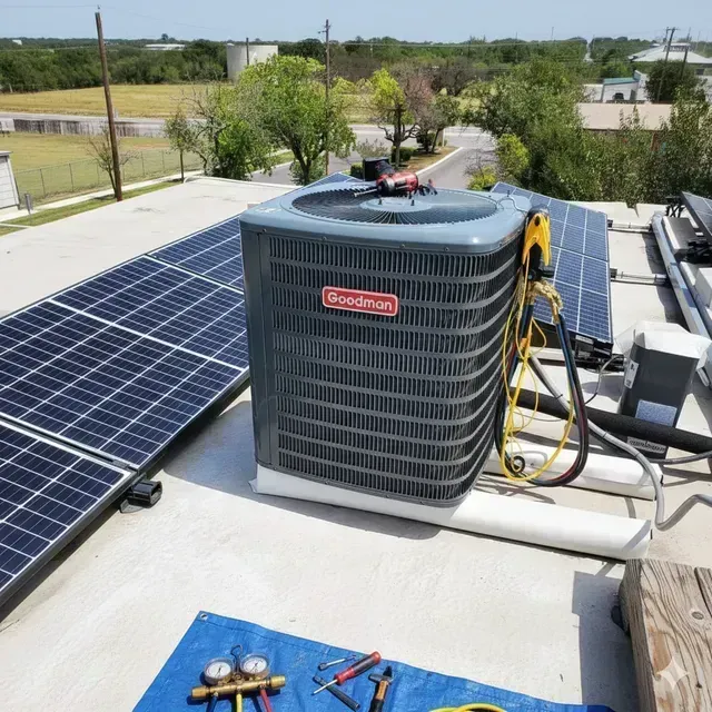 Solar panels and a rooftop HVAC unit with tools on a white roof under a clear sky