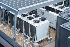 Rooftop HVAC units with large fans installed beside a building