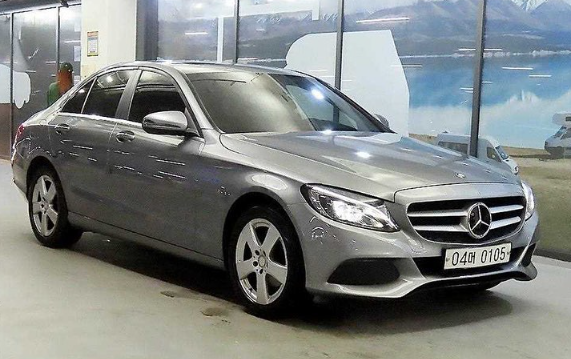 A silver mercedes benz c class is parked in a showroom.