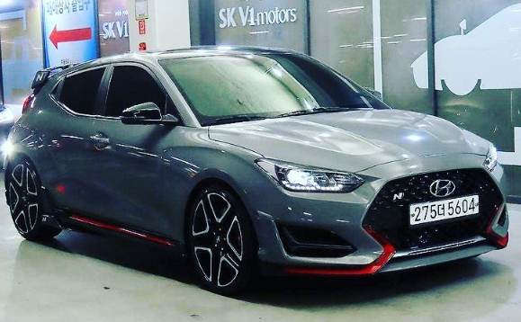 A gray hyundai veloster is parked in a parking lot.