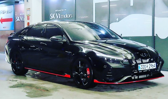 A black car with red trim is parked in a garage.