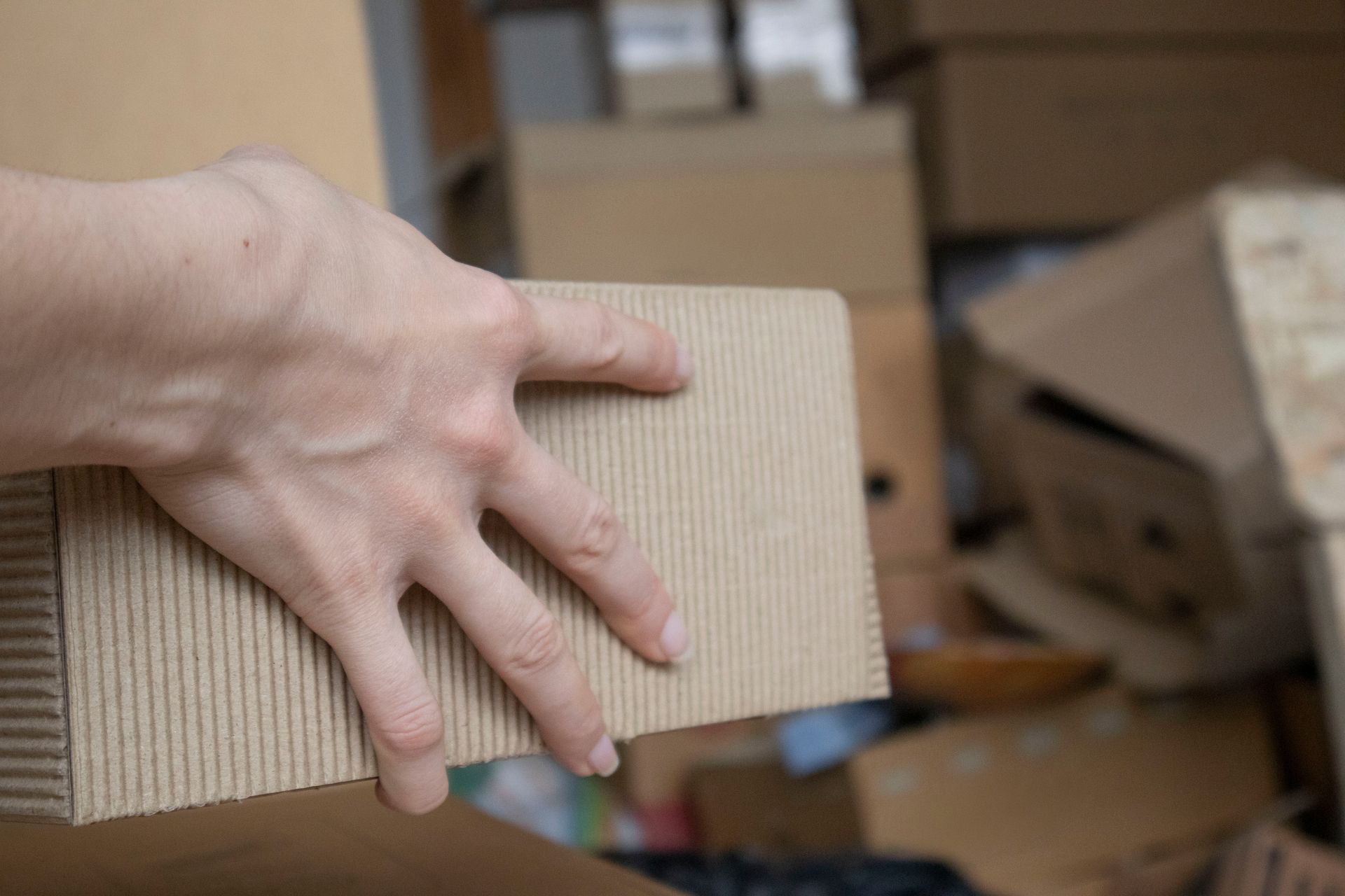 A close-up of a hand holding a cardboard box and sorting old things in storage.