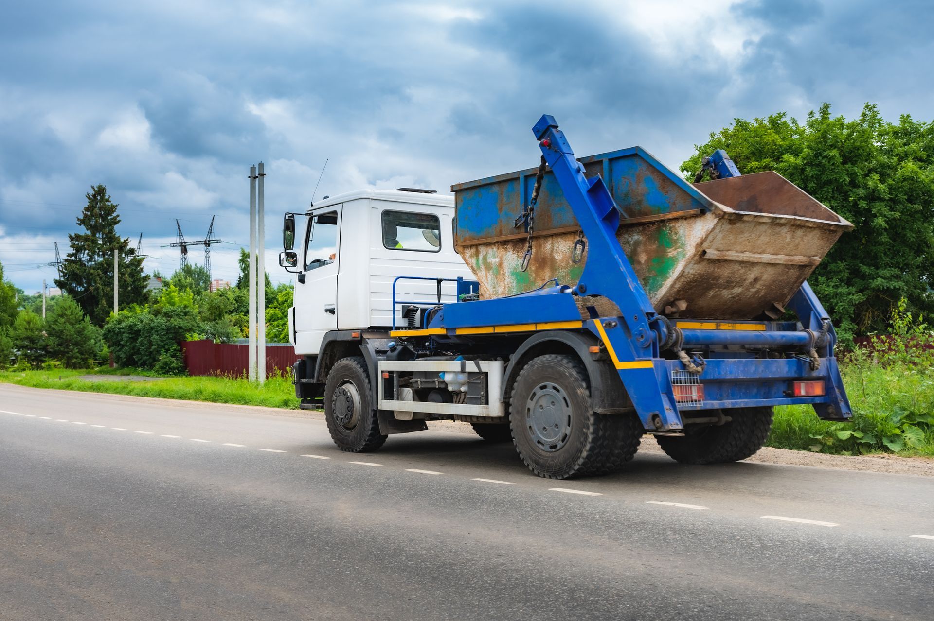 Rubbish removal truck near rural landscape.