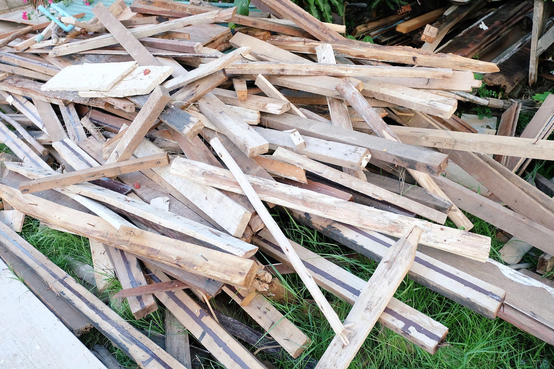 Construction debris with wood, insulation, and window frames in dumpster.