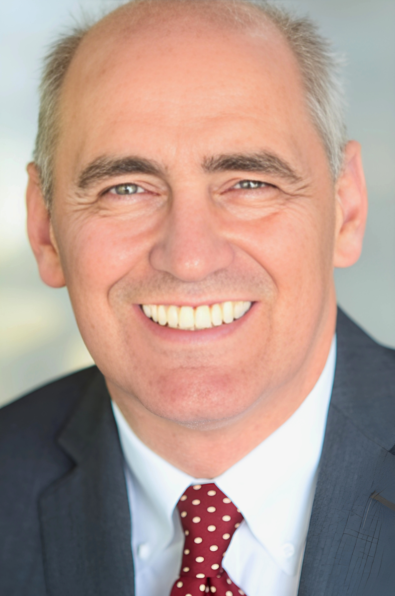 A man in a suit and tie is smiling for the camera
