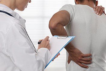 Female Doctor and Male Patient Suffering from Back Pain — Back Pain in Irvine, CA