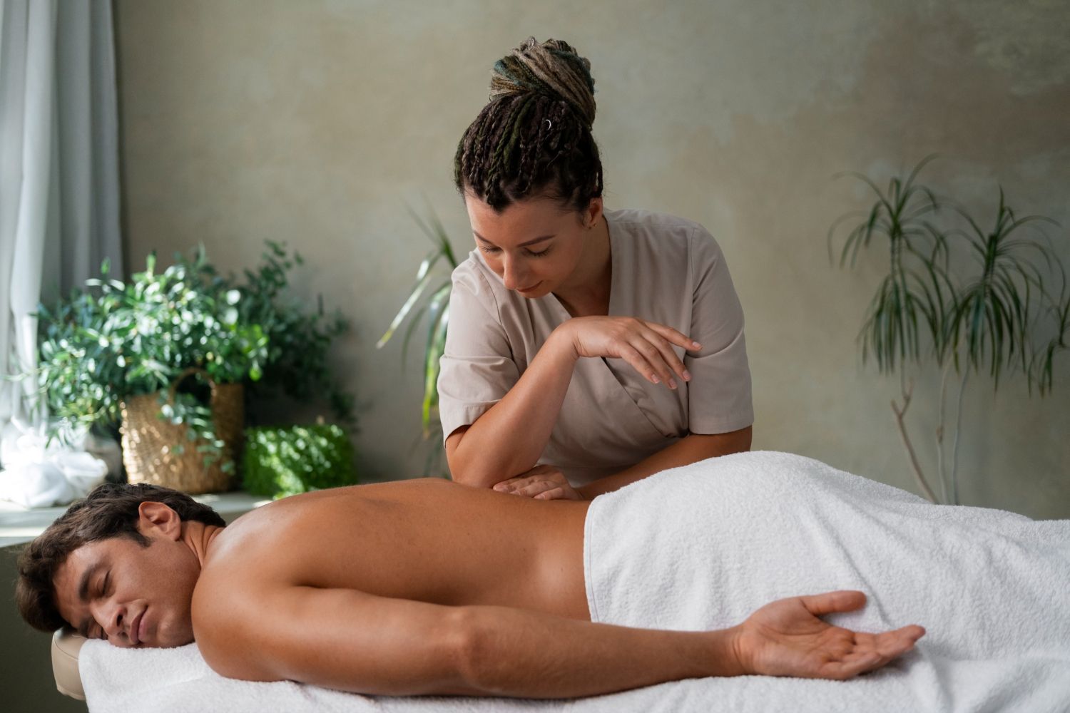 A man is laying on a table getting a massage from a woman.