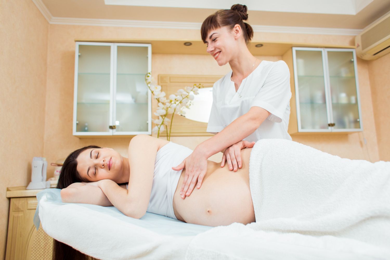 A pregnant woman is getting a massage at a spa.