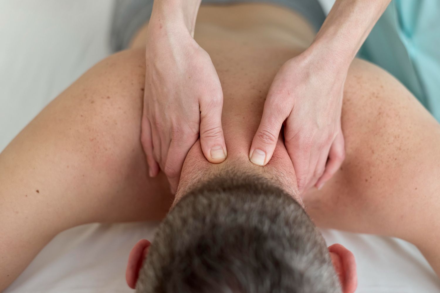 A man is laying on a bed getting a massage from a woman.
