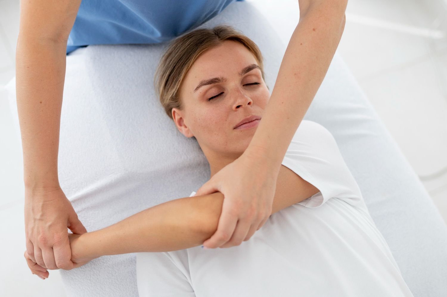 A woman is getting a massage on her elbow while laying on a bed.