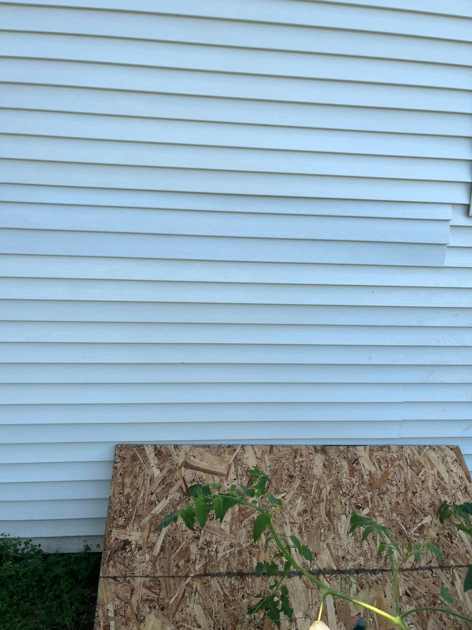 A white house with a piece of plywood in front of it.