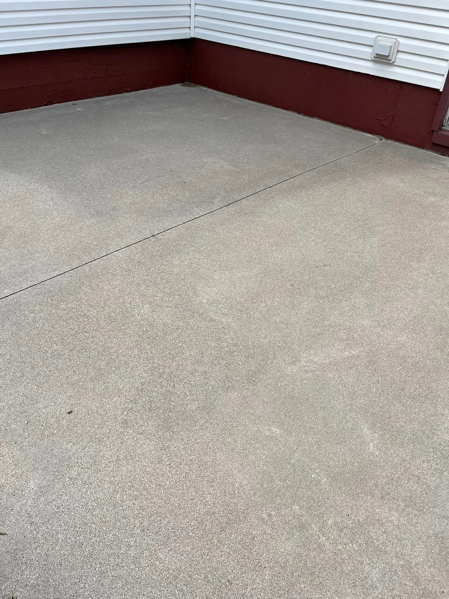 A concrete patio with a red siding and a white house in the background.