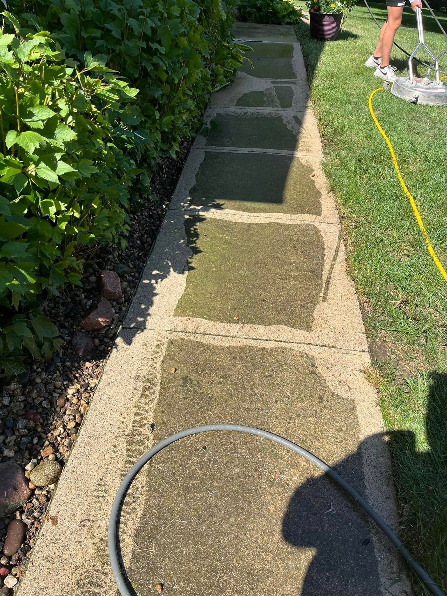 A person is cleaning a sidewalk with a hose.