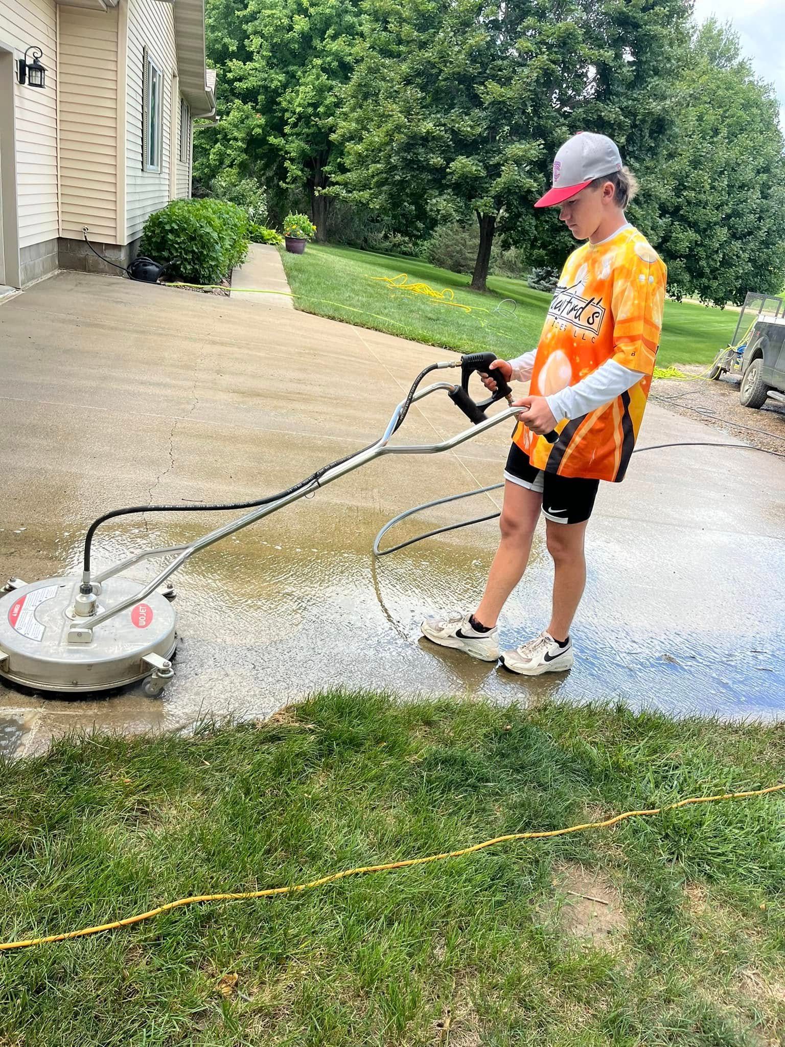 A woman is using a pressure washer to clean a driveway.
